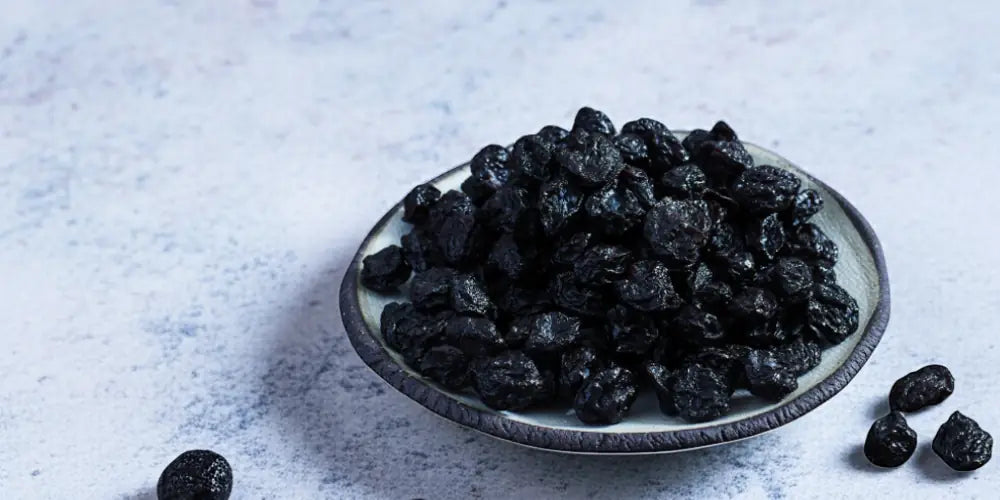 Dried organic blueberries  on a plate with a light blue white background